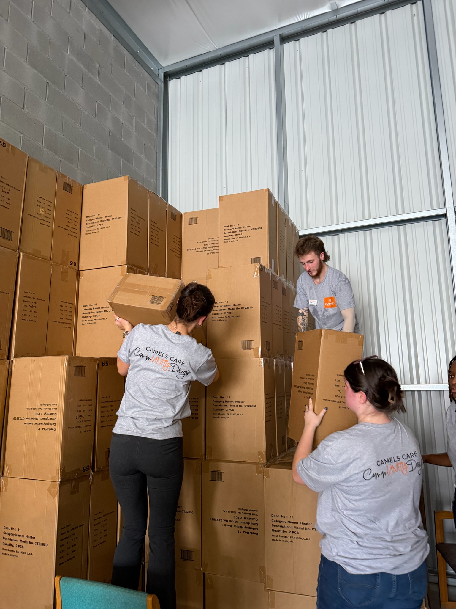 Volunteers stacking boxes in storage unit.