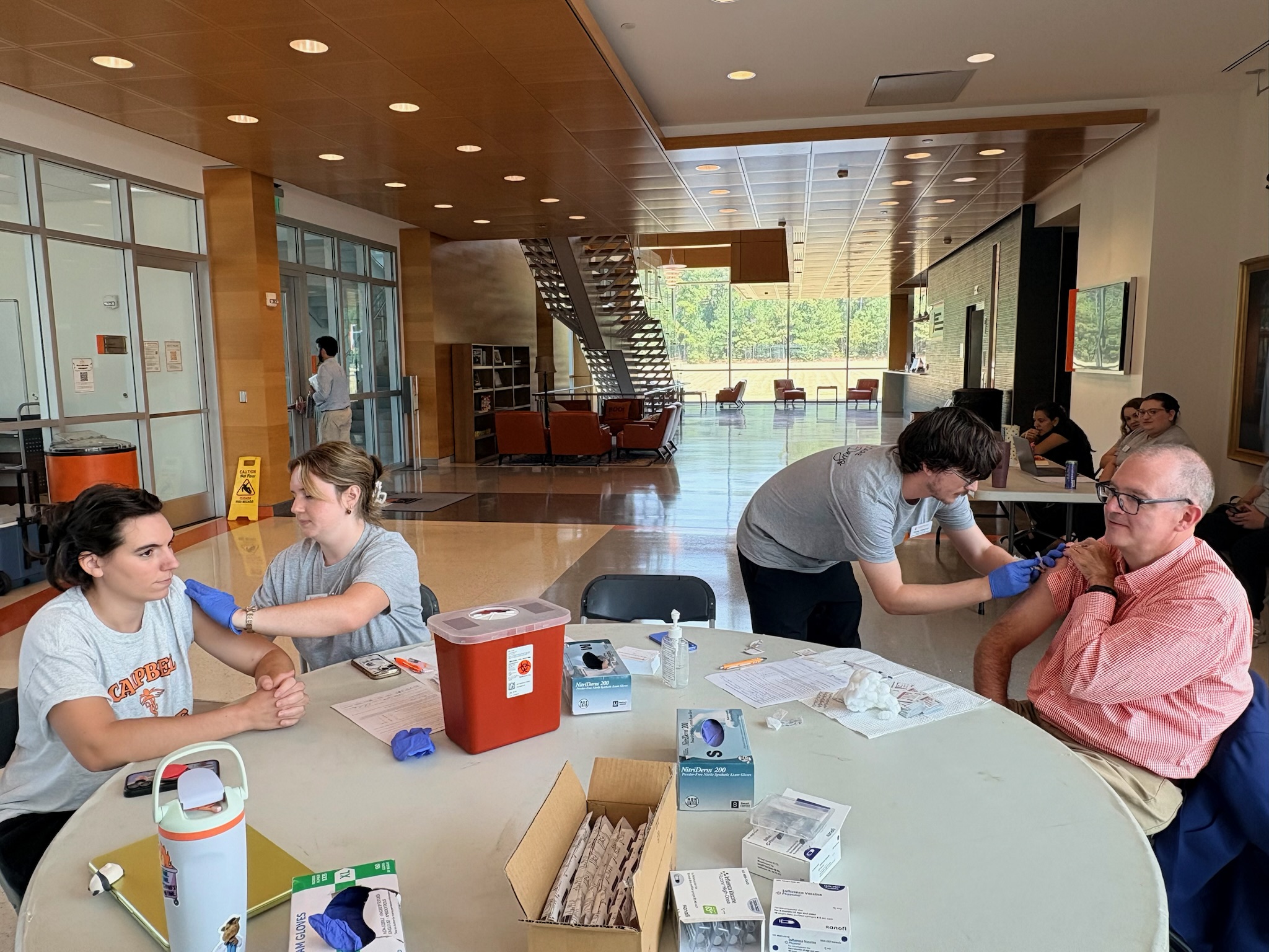 Two students administering flu shots to faculty members.