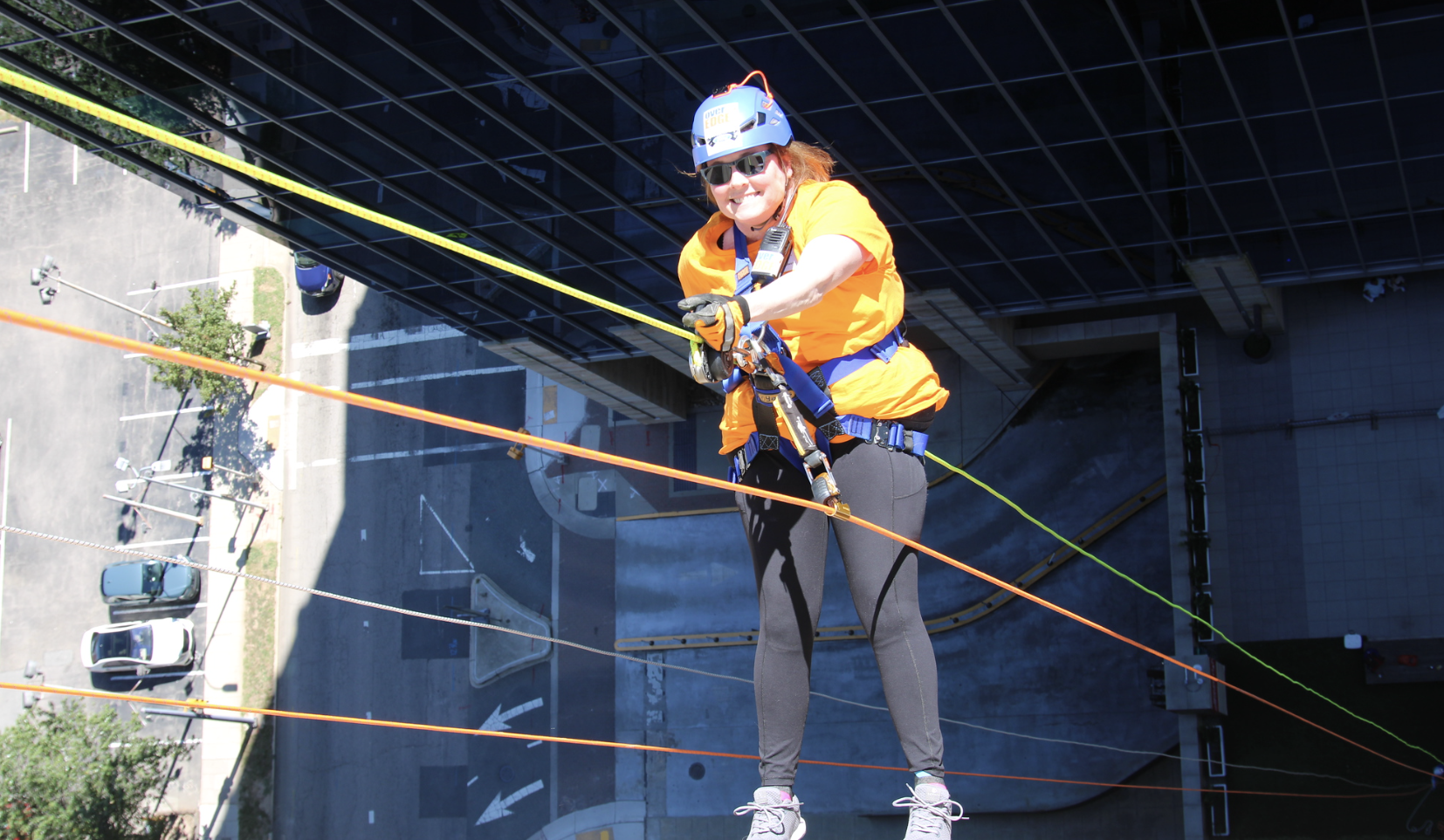 Photo of Cynthia Edwards, law student, hanging off the side of building in downtown Raleigh while rappelling