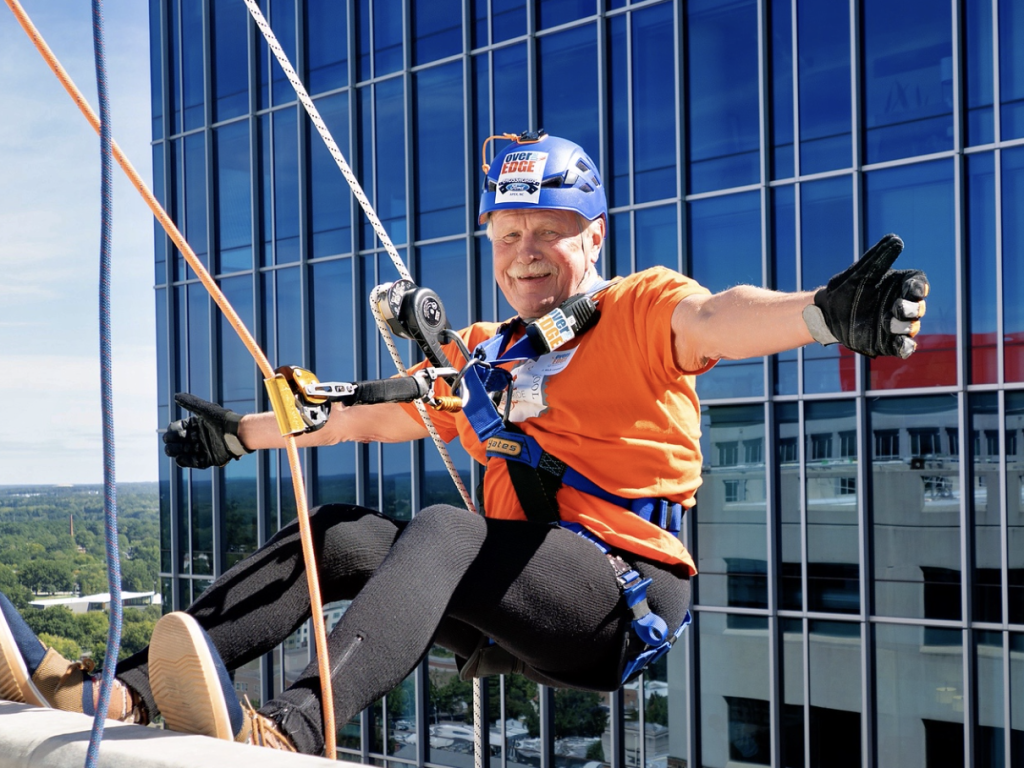 Photo of Dean Leonard hanging over the edge of a tall building in downtown Raleigh for Special Olympics NC fundraiser