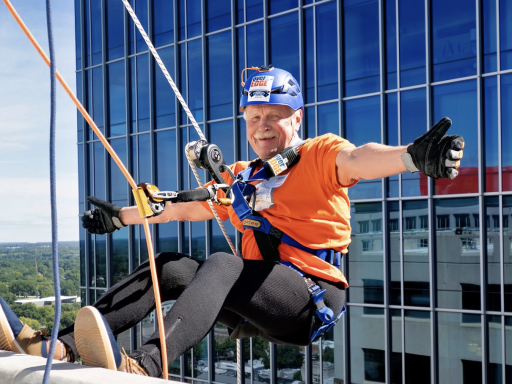 Photo of Dean Leonard hanging over the edge of a tall building in downtown Raleigh for Special Olympics NC fundraiser