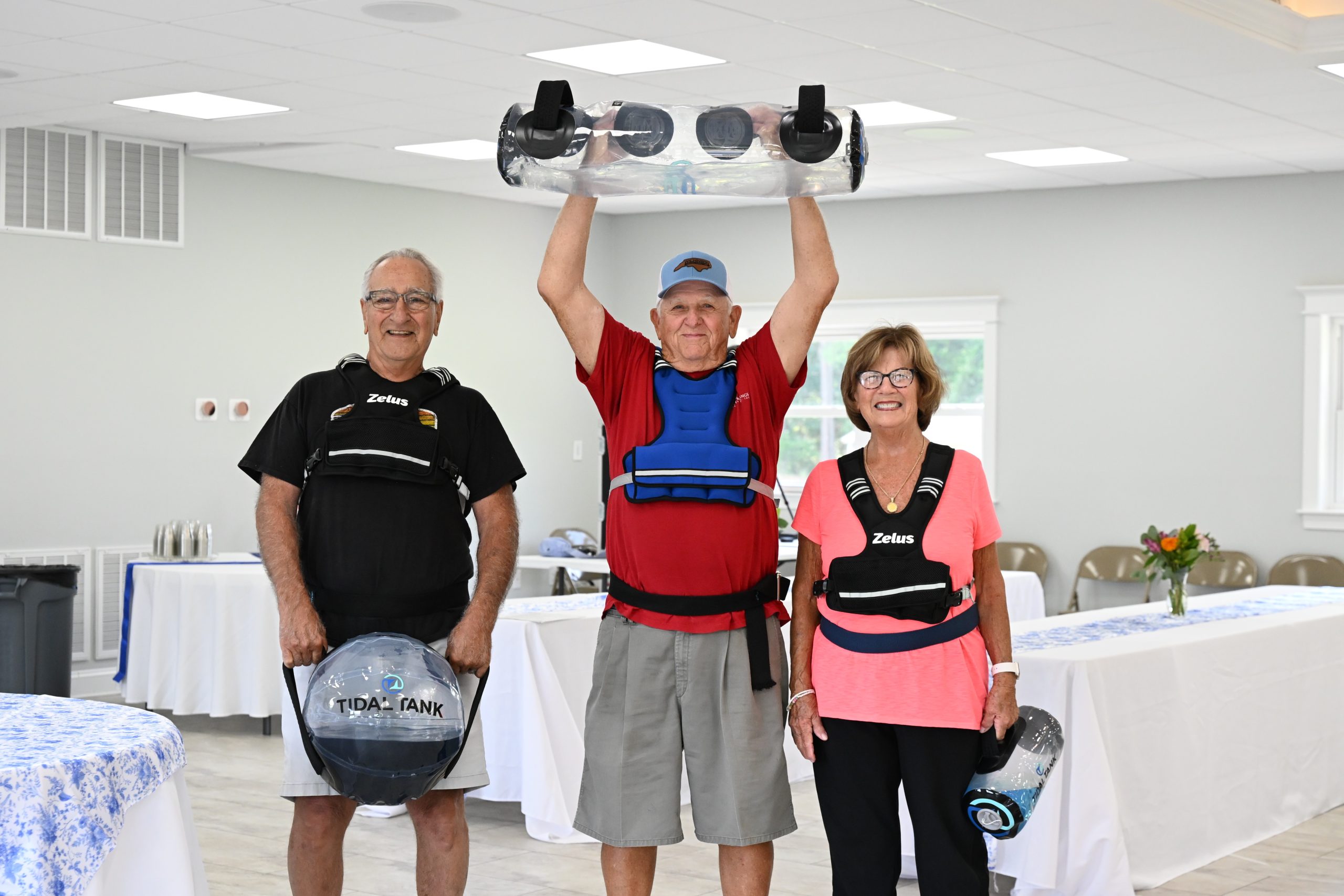 Three senior adults holding physical therapy equipment