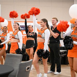Campbell cheerleaders raise orange and black pom-poms during a performance at the Alumni Block Party.