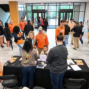 Guests check in at a table as alumni and families gather in the Student Union lobby for the Alumni Block Party.
