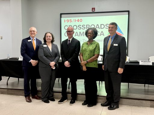 Five professionals in business attire standing at the front of a conference room