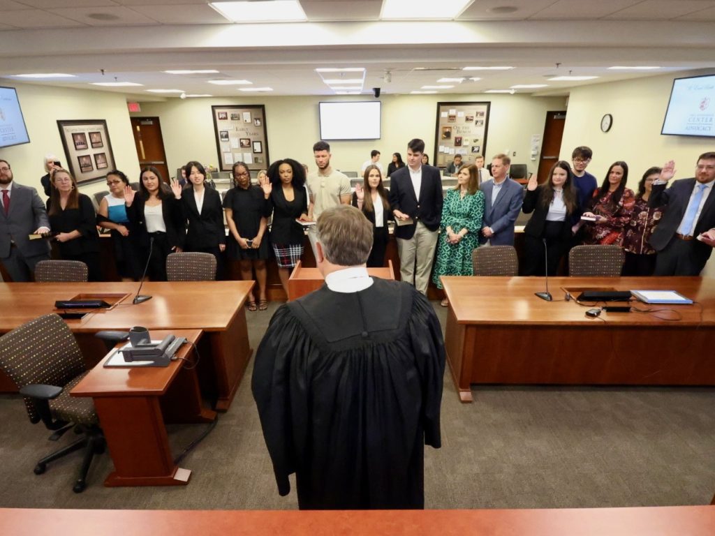 Photo of Judge Jeffrey Foster '90 standing in front of group of Campbell Law alumni and their families in the Britt Courtroom as they are sworn in