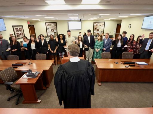 Photo of Judge Jeffrey Foster '90 standing in front of group of Campbell Law alumni and their families in the Britt Courtroom as they are sworn in