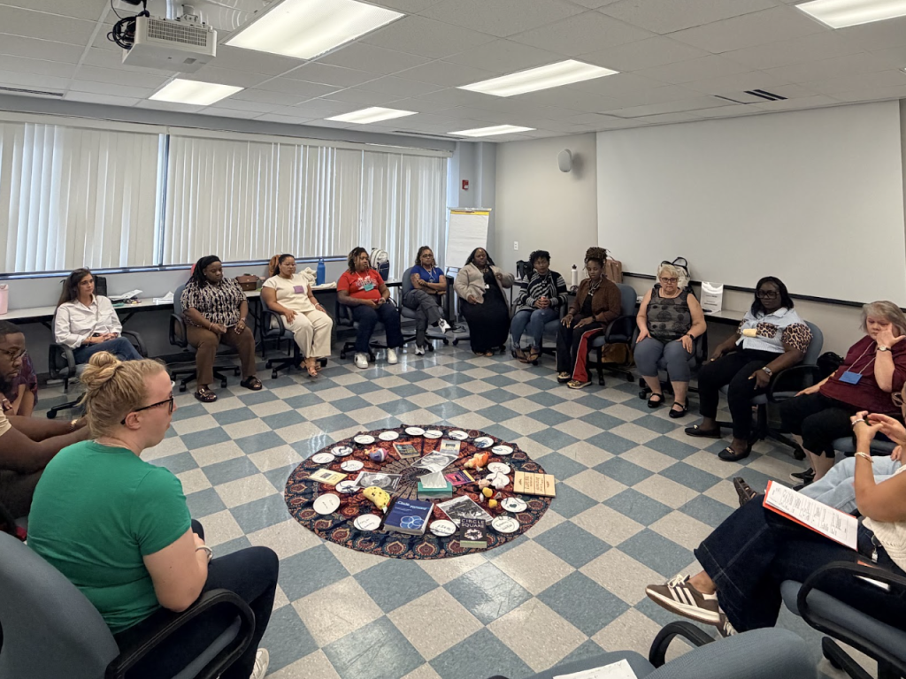 Photo of a large group of educators sitting in a circle in a conference room with Campbell Law Professor Jon Powell '98