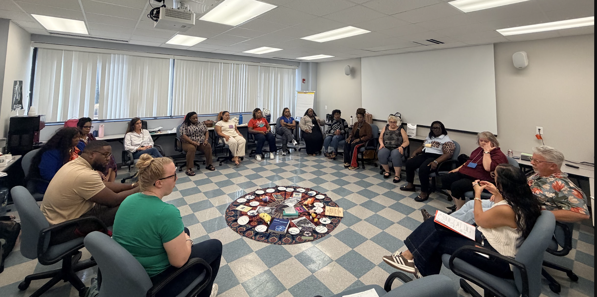 Photo of a large group of educators sitting in a circle in a conference room with Campbell Law Professor Jon Powell '98