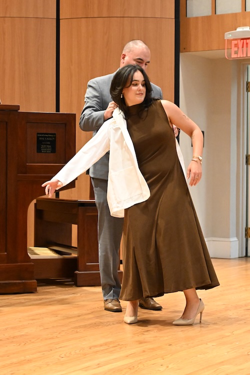 Photo of new student doctor receiving her white coat.