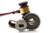 Steel cogwheels on judge's wooden gavel background