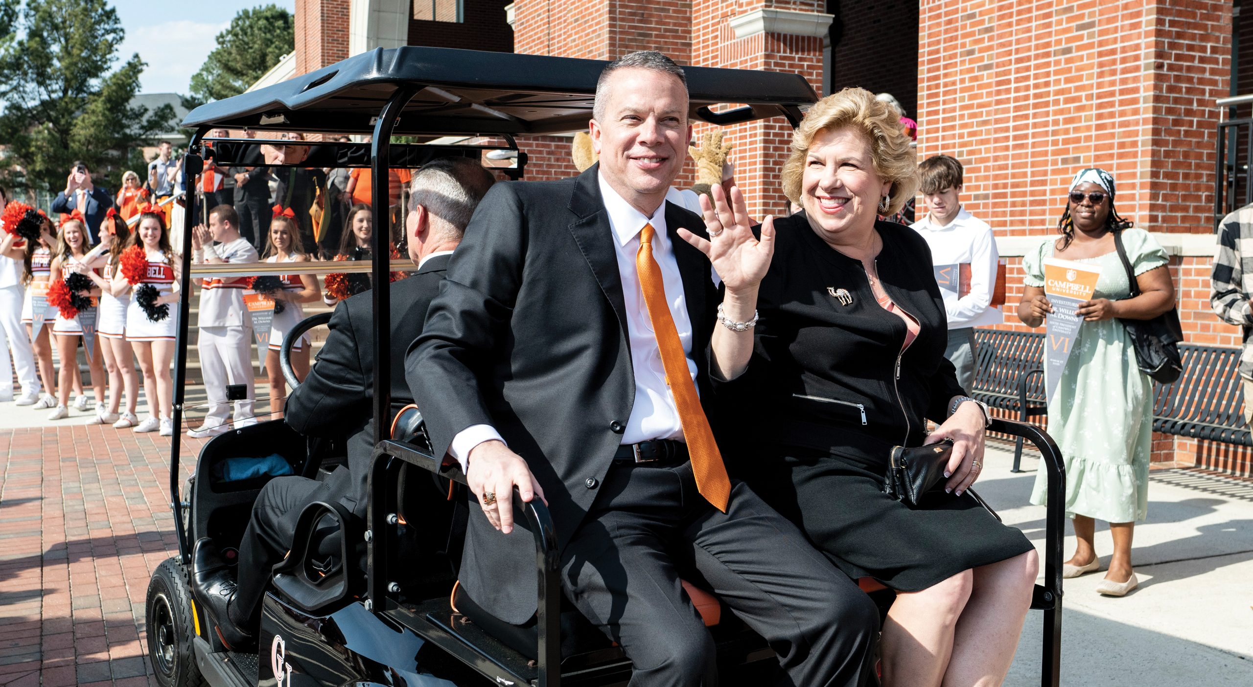 The president and first lady wave to students from the back of a golf cart following Dr. Downs' investiture ceremony in March.