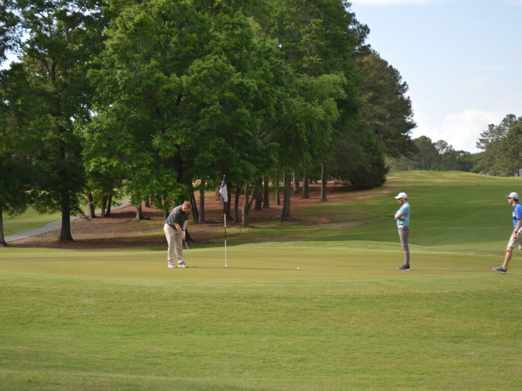 Two members of the harnett health team putting on the green at cphs golf tournament