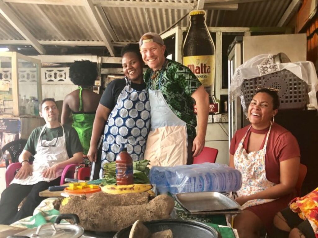 Photo of law student and Professor Shawn Fields hugging in front of table of food while in a cooking class in Ghana