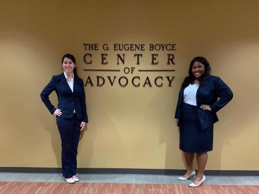 Photo of Veterans Competition advocates posing in front of the Gene Boyce Advocacy Clinic sign.