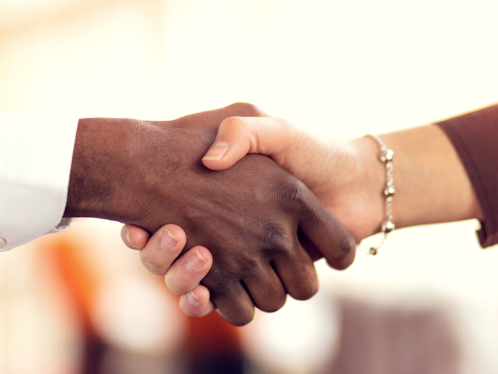 Photo of a black person's hand shaking a white person's hand