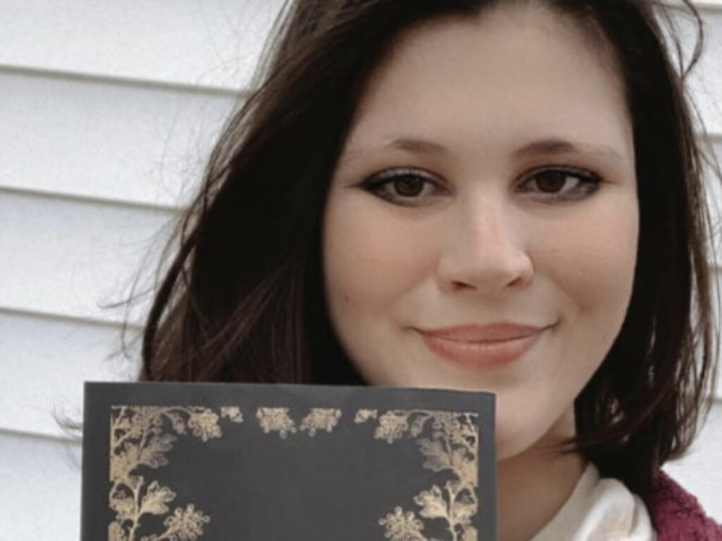 Photo of Emily Almanza '23 holding her novel