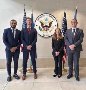 Photo of Campbell Law student Kevin Ferguson '27 posing with three others in the Rwanda, Africa, office of U.S. Embassy in Kigali.