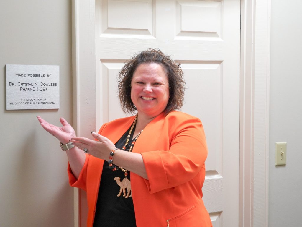 Crystal Dowless posing with her plaque inside the Alumni house