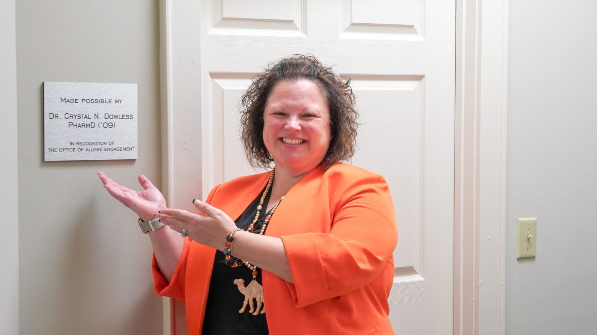 Crystal Dowless posing with her plaque inside the Alumni house