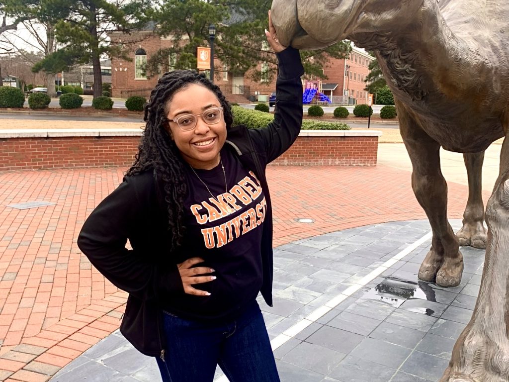 Shay Webb poses with the camel statue on campus.