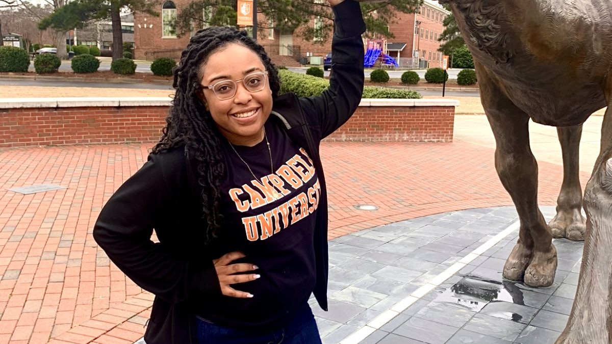 Shay Webb poses with the camel statue on campus.
