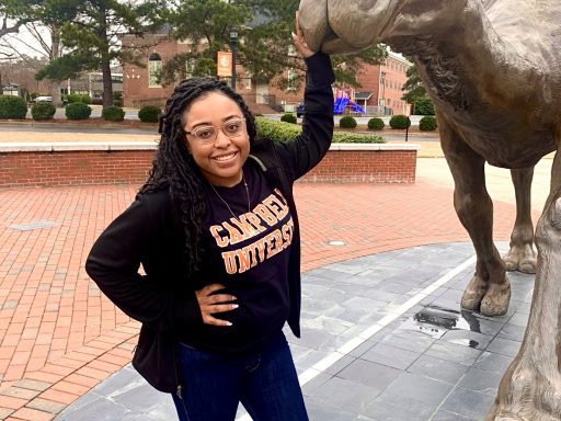 Shay Webb poses with the camel statue on campus.