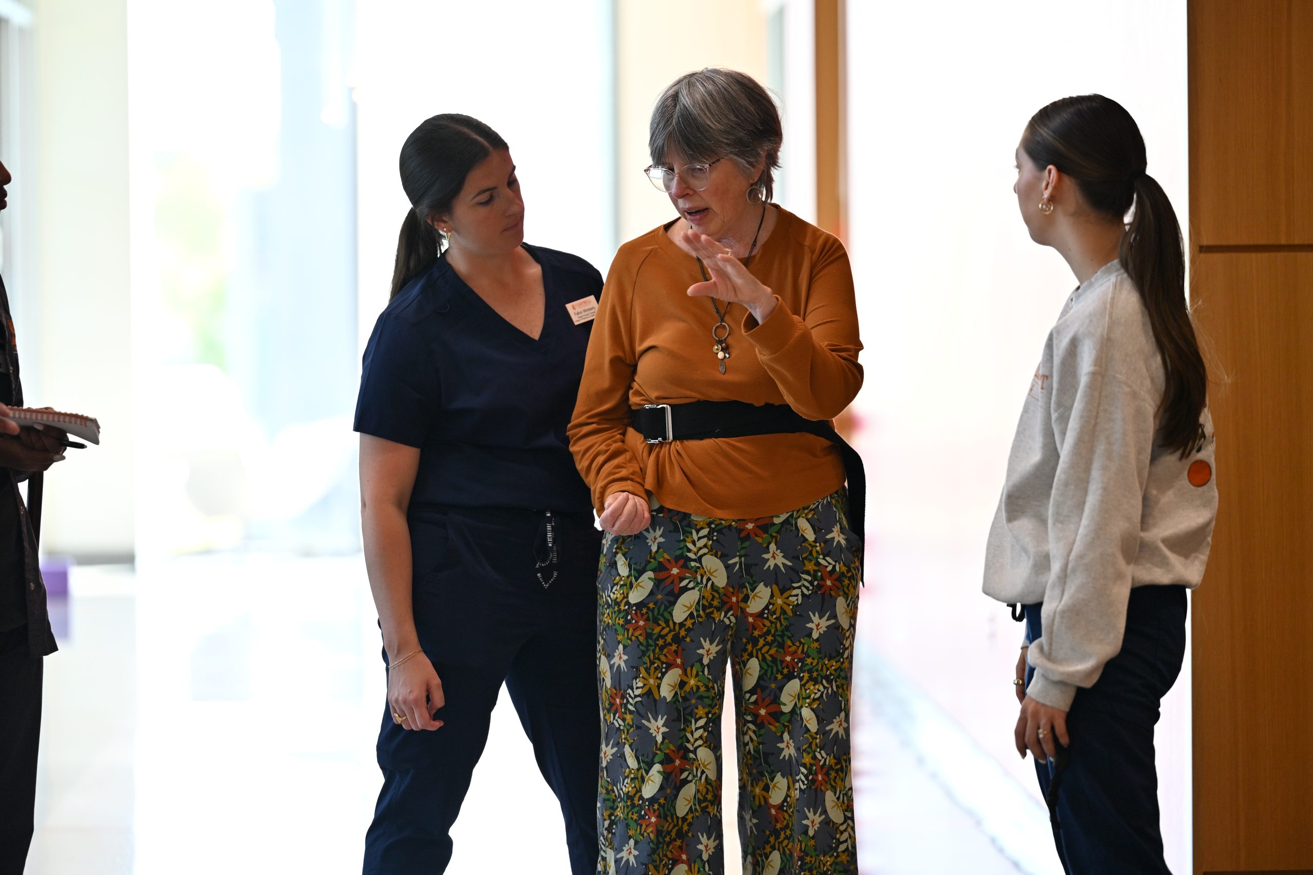 DPT students walking with a patient in the hallway.
