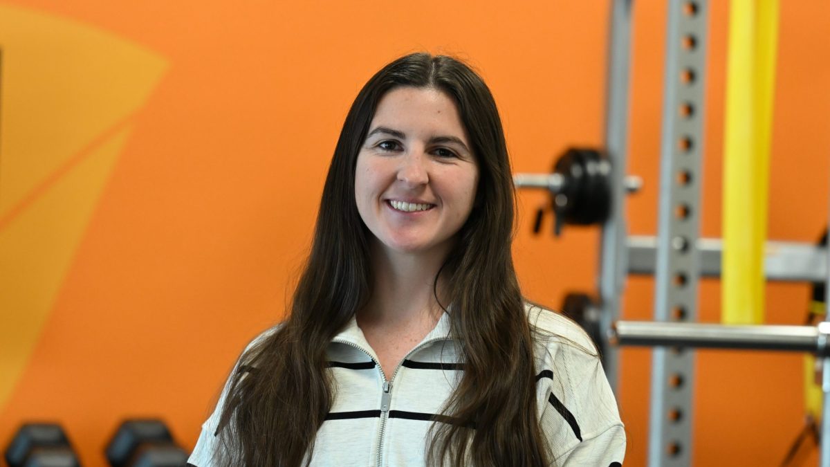 DPT student, Fallon Wimberly, looking at the camera with an orange colored wall in the background.