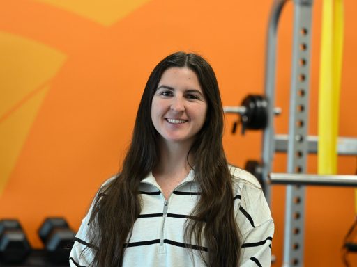 DPT student, Fallon Wimberly, looking at the camera with an orange colored wall in the background.