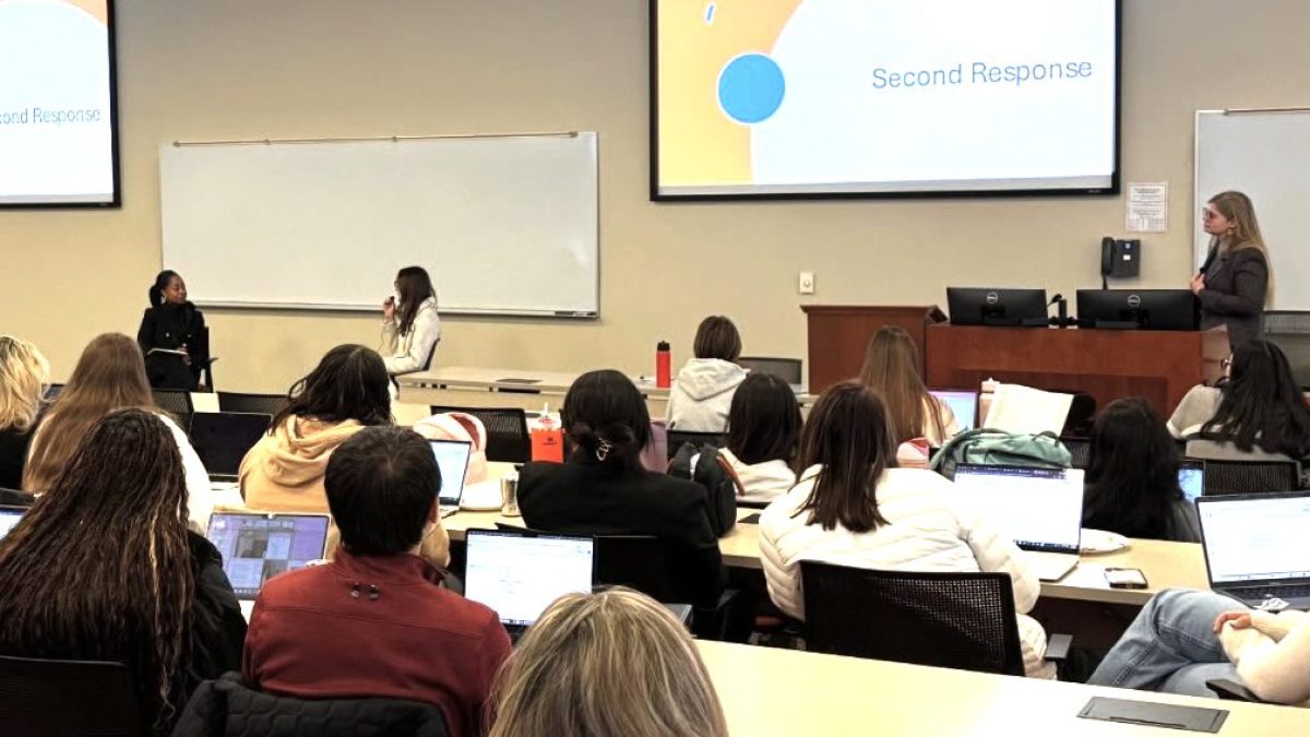 Photo of Career Center event where Darrah Perry '25 is doing a mock interview with a law student while Christiana Johnson looks on in front of classroom full of students