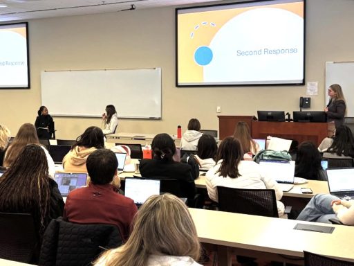 Photo of Career Center event where Darrah Perry '25 is doing a mock interview with a law student while Christiana Johnson looks on in front of classroom full of students