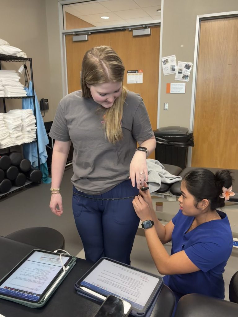 Two female PT students working together in class