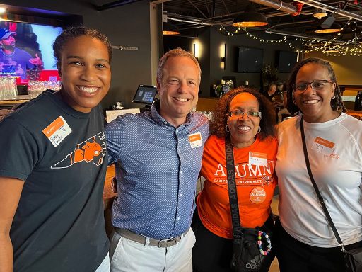 Four individual posing for a photo. All four have name tags while three individuals have Campbell University t-shirts on.