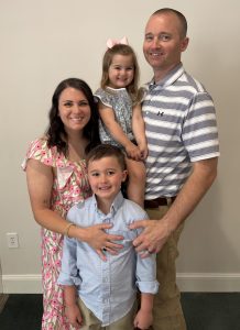 Lauren Banker ’14 poses with her husband and two children for a family photo.