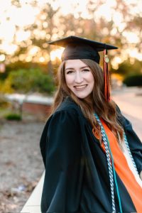 Hannah Byrd Collins ’20 smiles in her Campbell University cap and gown during an outdoor graduation portrait.