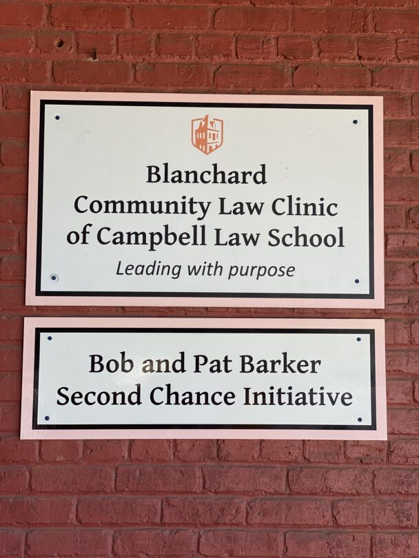 Photo of Blanchard Community Law Clinic sign that also has the words of Campbell Law School and Leading with purpose and Bob and Pat Barker Second Chance Initiative