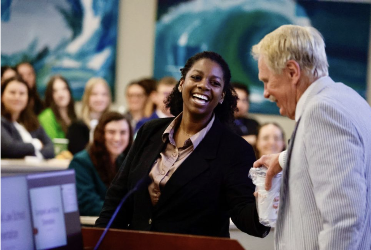 Photo of a student laughing with Dean J. Rich Leonard in front of group of students in Room 105 during Orientation